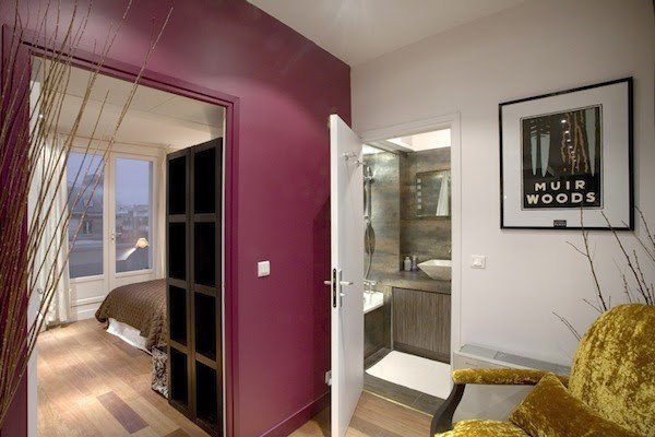 The bedroom and glass shower viewed from a colorful sitting corner.
