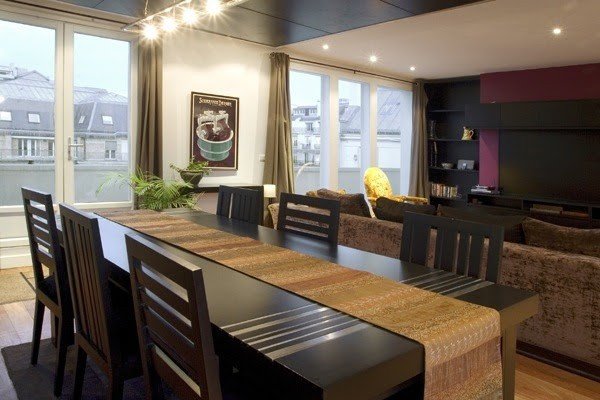 The dining table beside tall windows and the adjoining salon.
