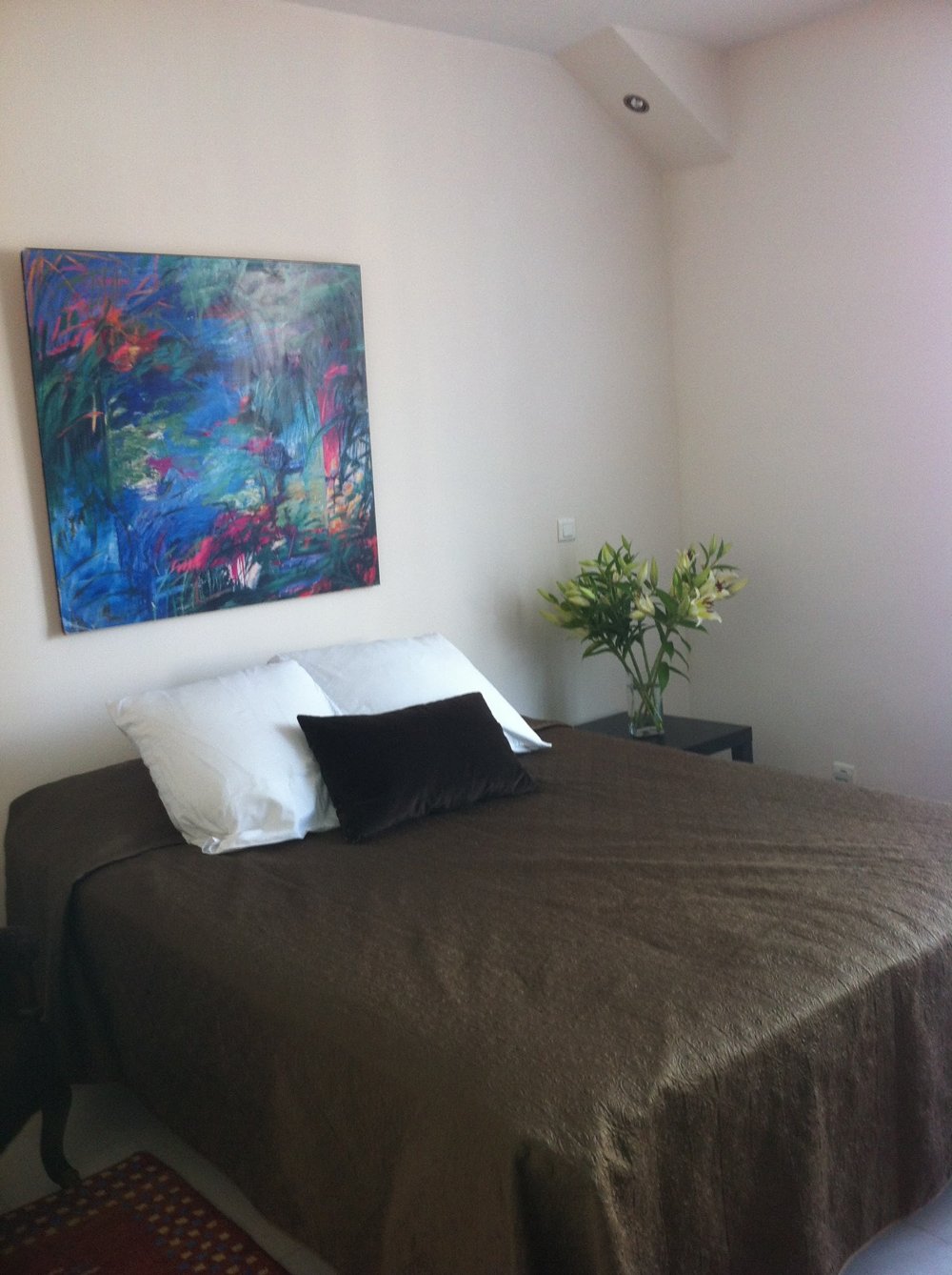 A double bed beneath colorful artwork in the fourth-floor apartment.