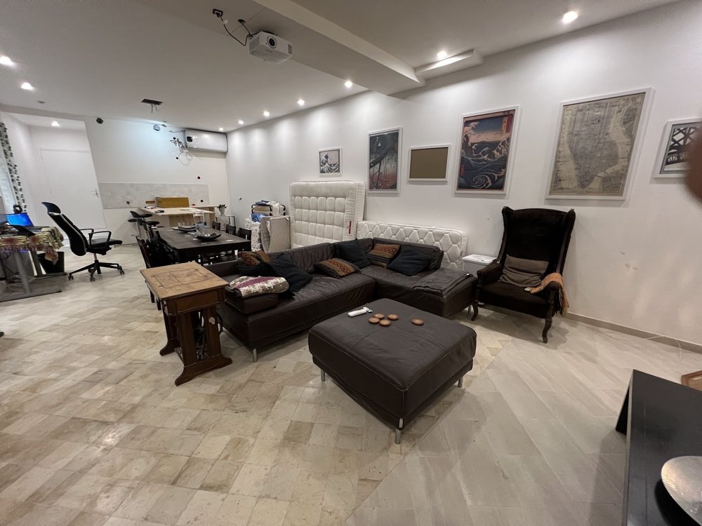 A wide view of the RDJ lower level with a corner sofa, dining table, artwork, and bookcases.